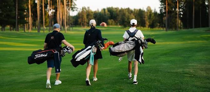 Kolme golfaajaa kävelemässä pallolaukkujen kanssa väylällä St. Laurence Golfin kentällä